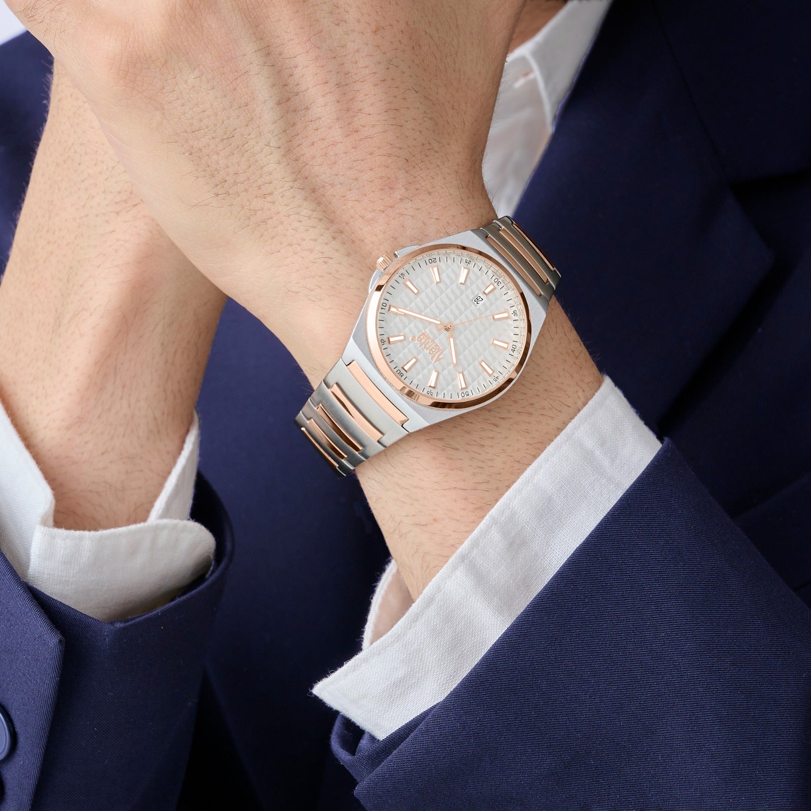 Person wearing a rose gold watch with a white strap on a dark suit background